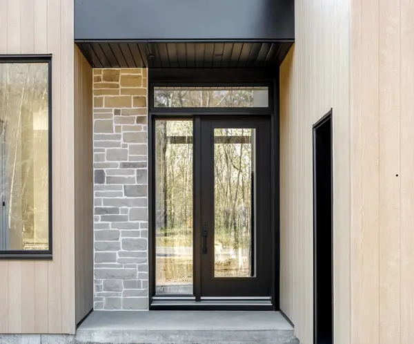 Yellow Vaillancourt Doors and Windows double exterior entrance door to a beige stone house.