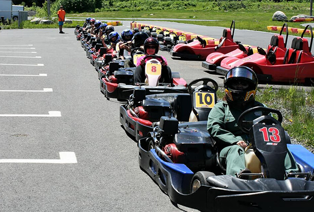 A line of several go-karts parked outside with Vaillancourt Doors and Windows employees