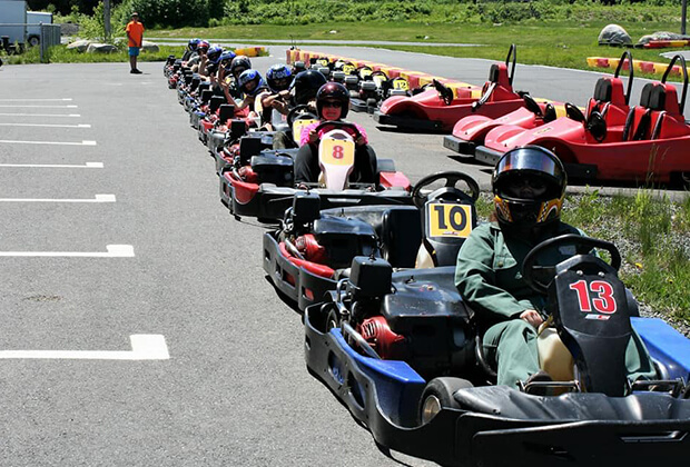 Une file de plusieurs voiturettes de go-kart stationnées à l’extérieur avec des employés de Vaillancourt Portes et Fenêtres