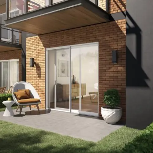 White model of the R-630 PVC patio door from Vaillancourt Doors and Windows, seen from the garden level of an apartment.