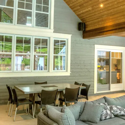 Design of seven white PVC Vaillancourt Doors and Windows sash windows seen from a large covered outdoor terrace.