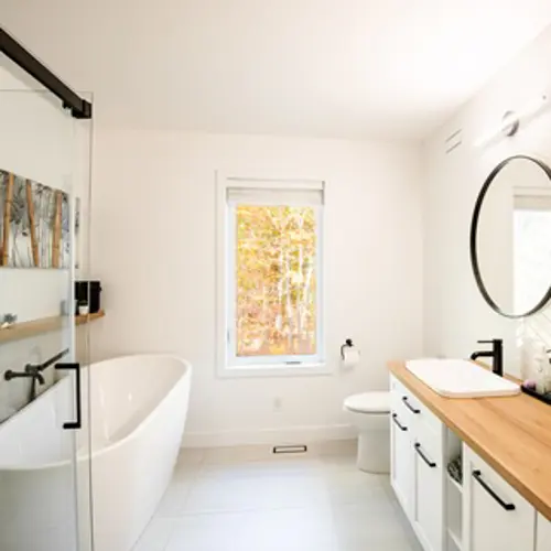 Three white Vaillancourt Doors and Windows casement windows in PVC or hybrid in a minimalist bathroom for more natural light.