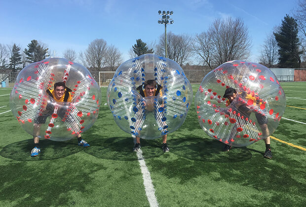 Three Vaillancourt employees in giant transparent bubbles on an outdoor soccer field for an activity